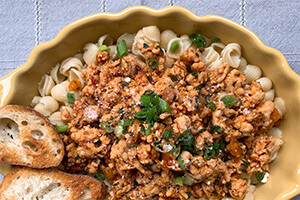 Turkey bolognese pasta on a plate with extra bread on the side