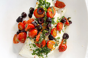 a baked tomato olive cod fish on a plate